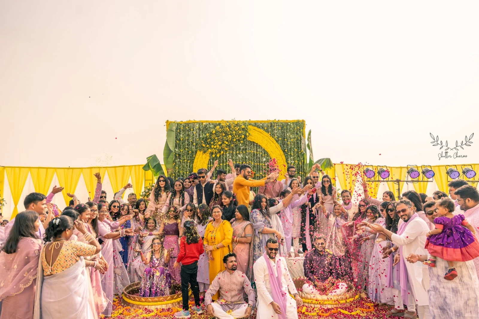 Guests shower flower petals during a festive outdoor haldi ceremony