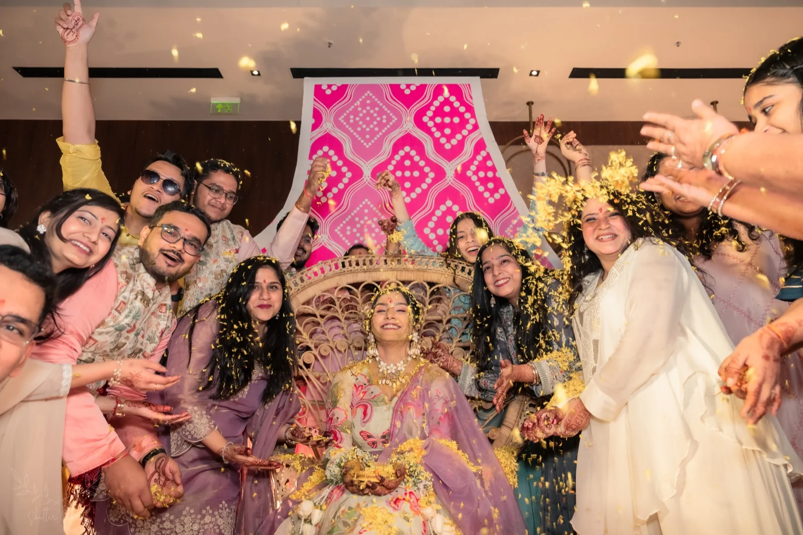 Friends shower marigold petals on the bride at her haldi