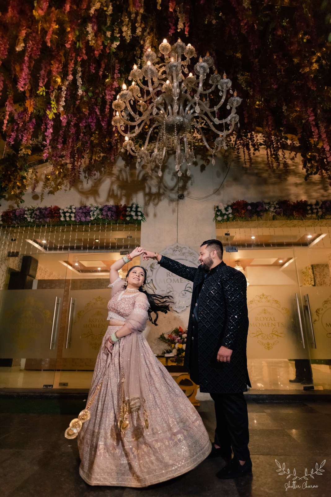 Couple twirling beneath a chandelier outside the wedding venue
