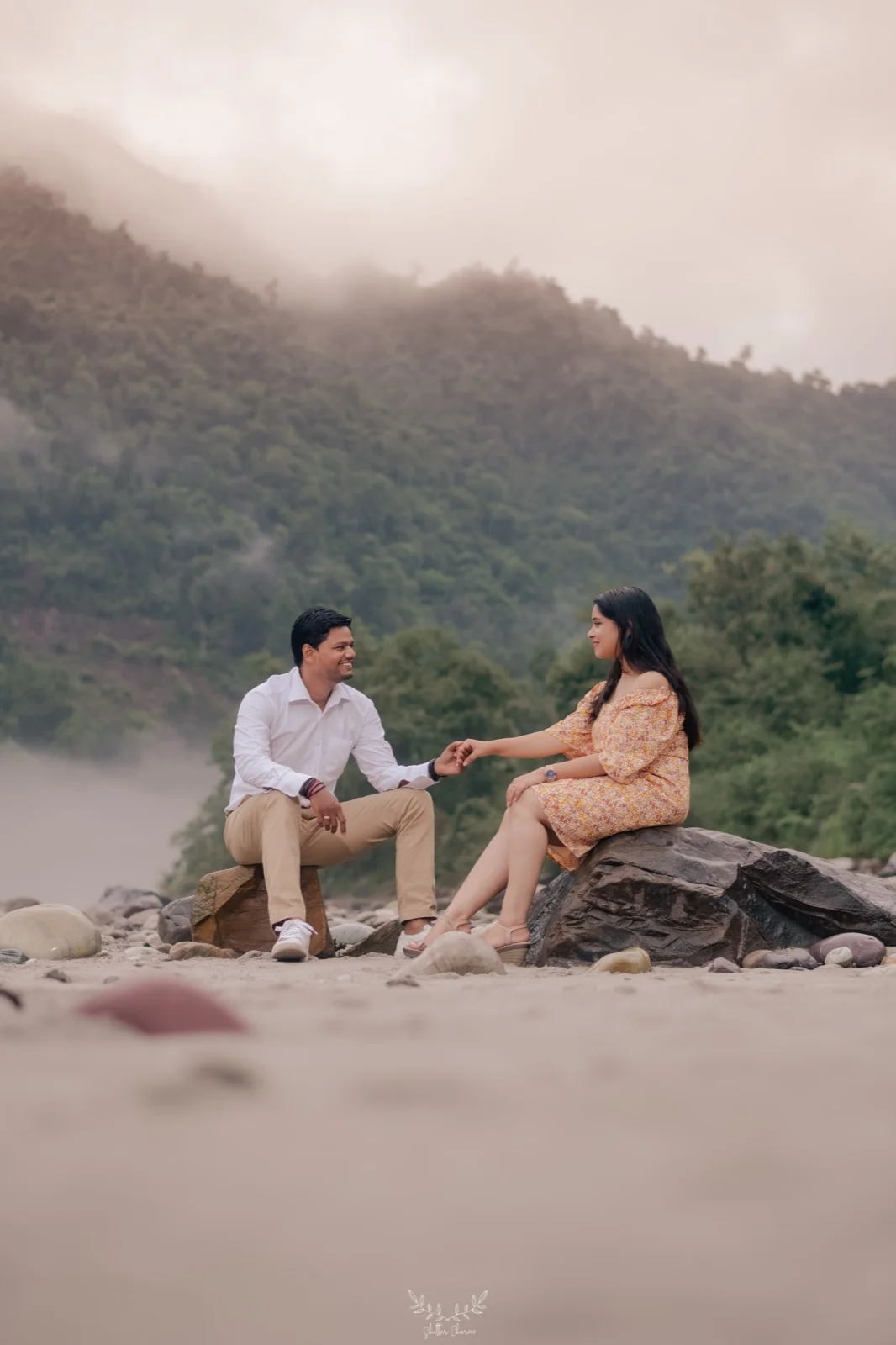 Couple holding hands on a misty riverside during pre-wedding shoot