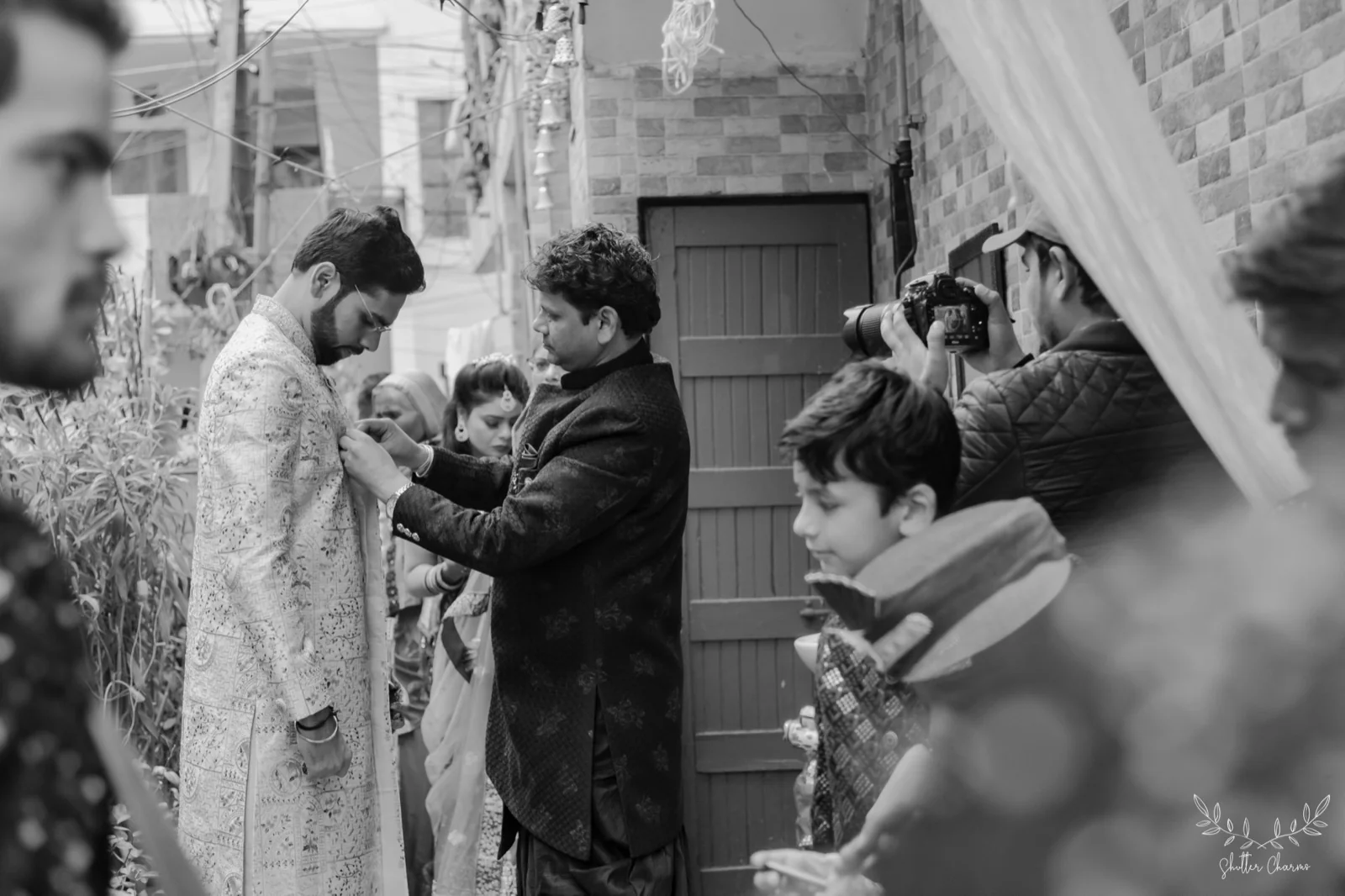 Family member adjusting groom's sherwani in a candid getting-ready moment