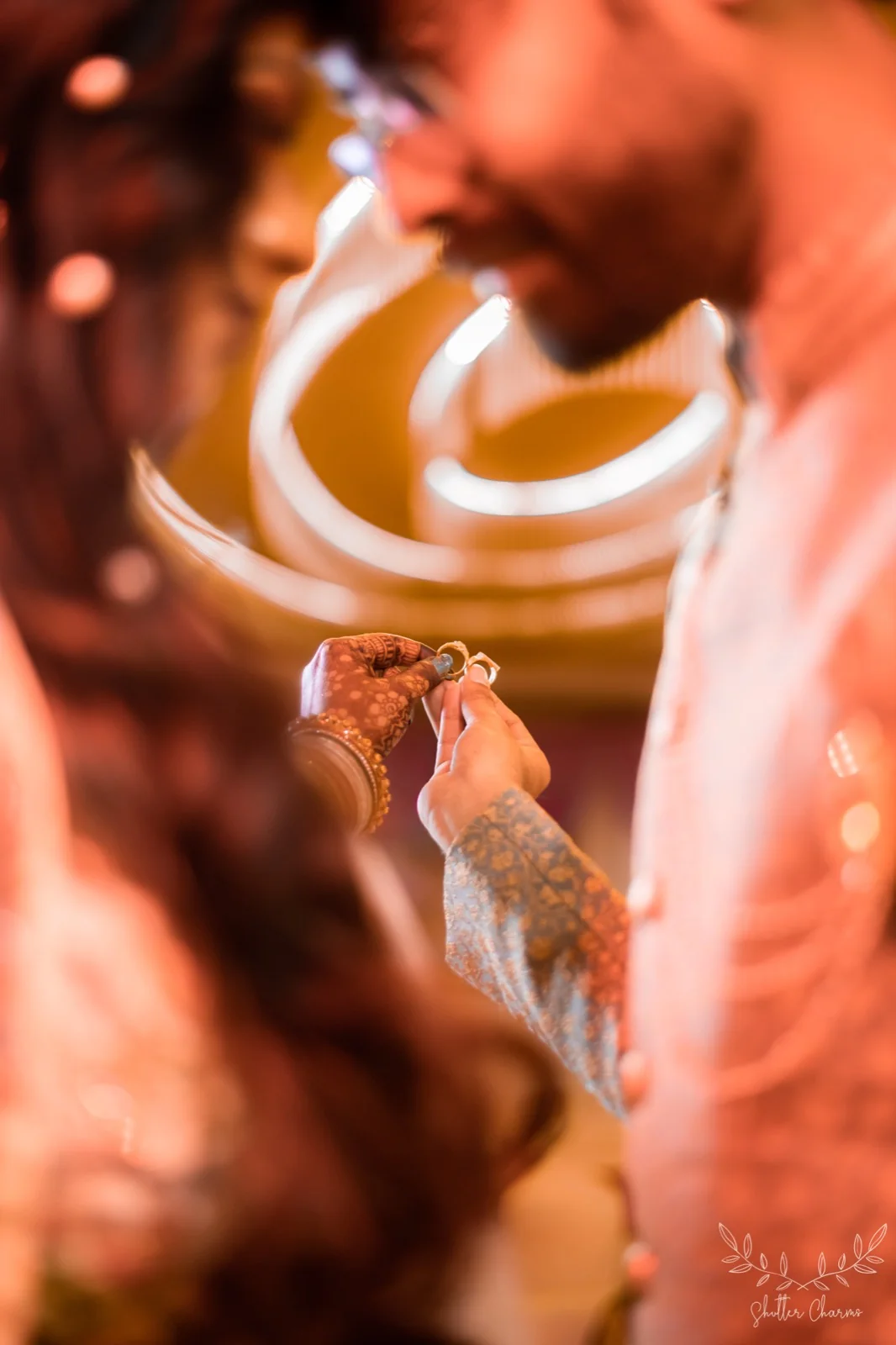 Close-up of couple's hennaed hands holding wedding rings