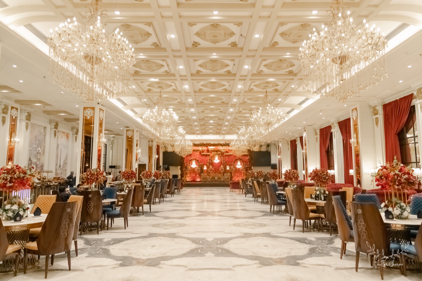 Chandelier-lit banquet hall with floral stage decorated for the reception