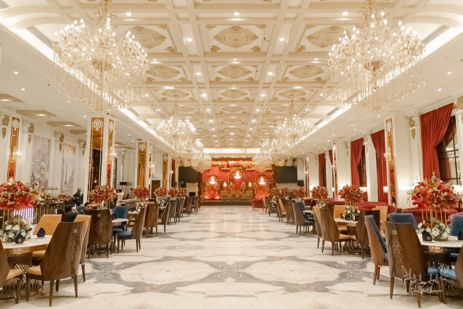Chandelier-lit banquet hall with floral stage decorated for the reception