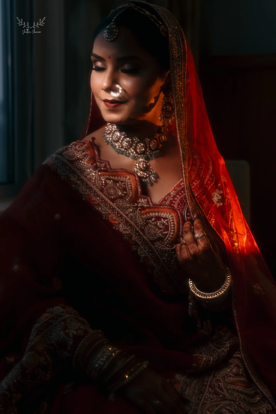 Bride in red bridal wear in dramatic window light